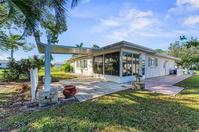 rear view of property featuring a yard, a sunroom, and a patio