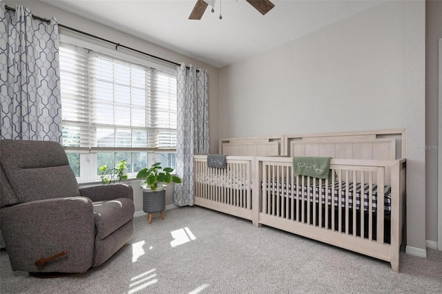 bedroom with a nursery area, ceiling fan, and carpet floors