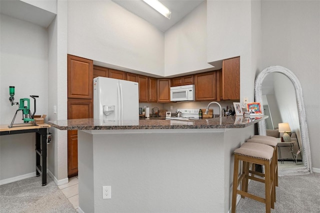 kitchen featuring white appliances, high vaulted ceiling, dark stone countertops, and light colored carpet