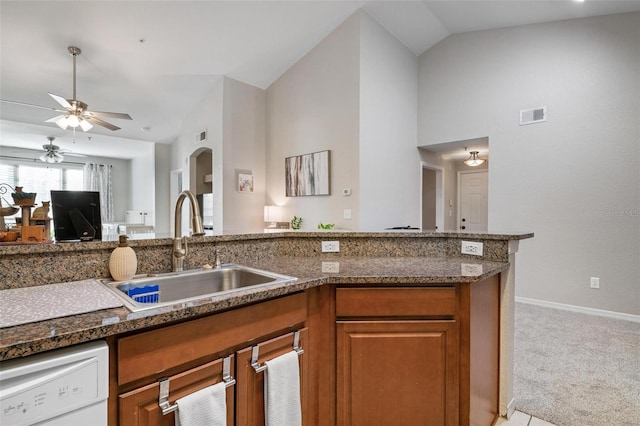 kitchen featuring lofted ceiling, dishwasher, dark stone counters, sink, and light colored carpet