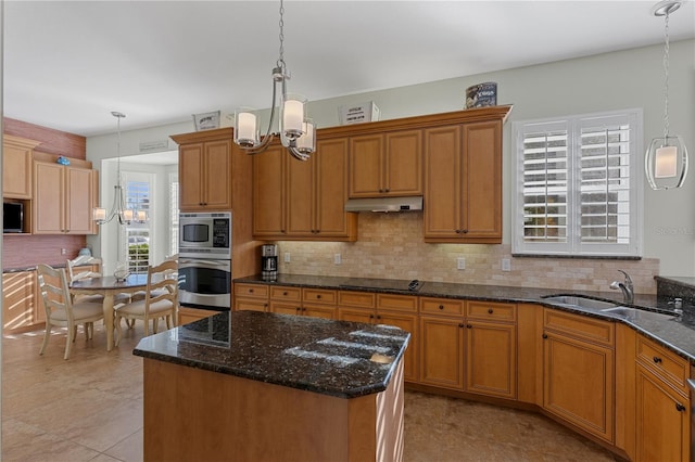 kitchen featuring a kitchen island, pendant lighting, stainless steel microwave, and sink