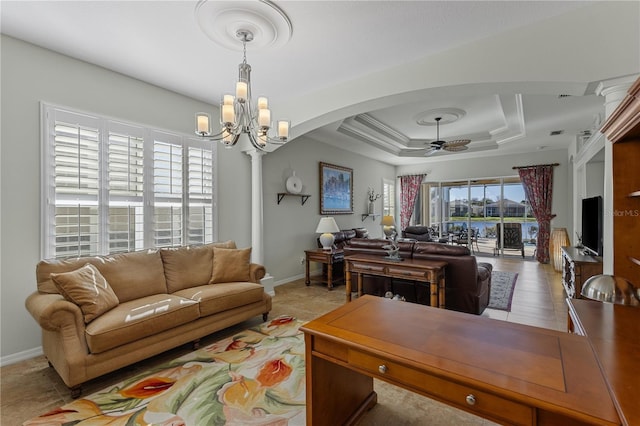 living room with crown molding, ceiling fan with notable chandelier, light tile patterned floors, and a raised ceiling