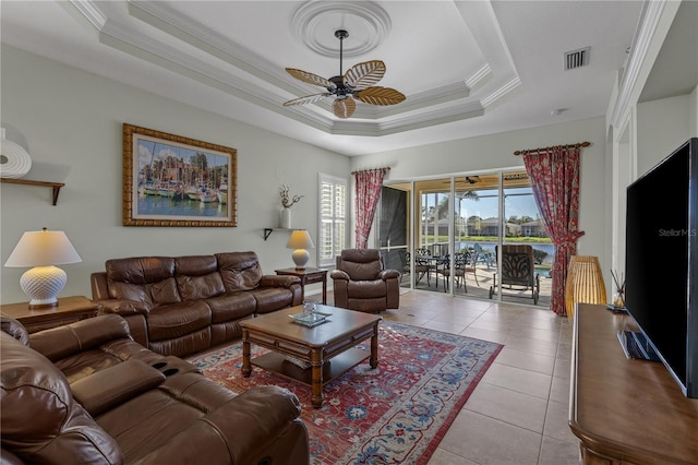 living room featuring light tile patterned floors, ceiling fan, a raised ceiling, and ornamental molding