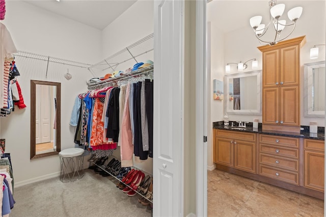 walk in closet featuring sink, light carpet, and a notable chandelier