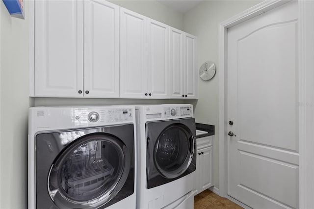 clothes washing area with washing machine and clothes dryer and cabinets