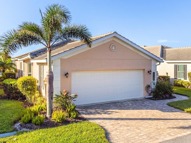 ranch-style house featuring a garage, decorative driveway, and stucco siding