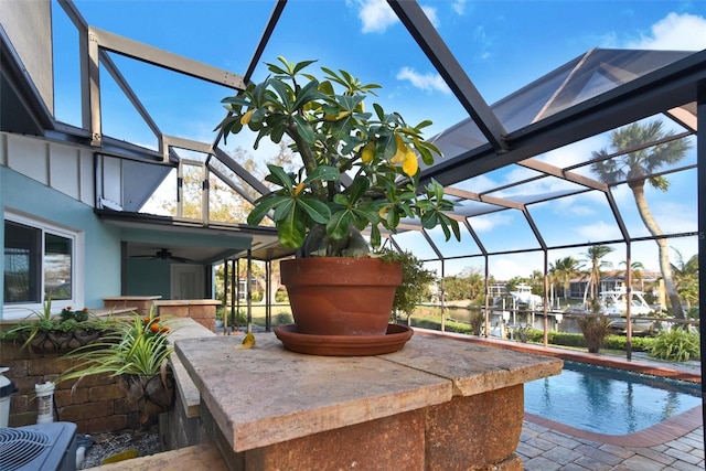 view of pool featuring glass enclosure, ceiling fan, a water view, and central AC unit