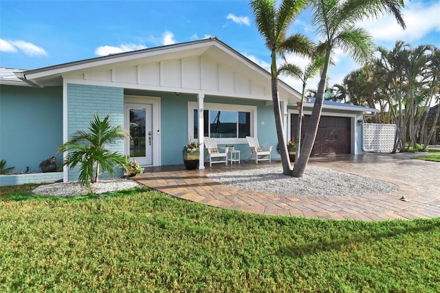 view of front of home featuring a front yard, a porch, and a garage