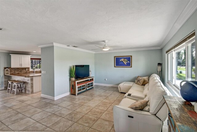 living room featuring light tile patterned floors, a textured ceiling, ceiling fan, and crown molding