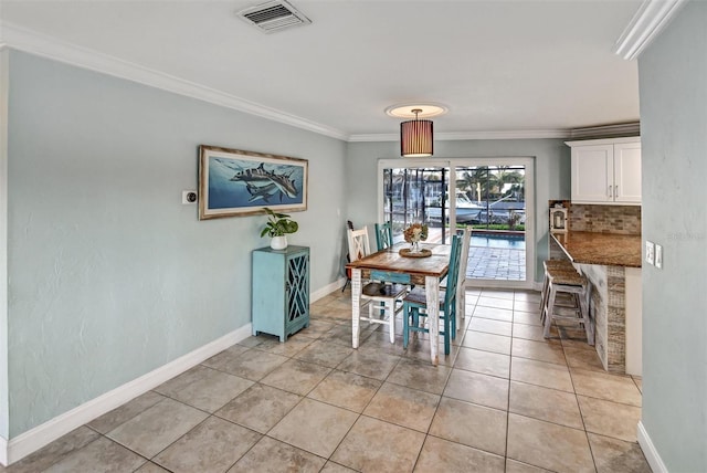 tiled dining space featuring crown molding