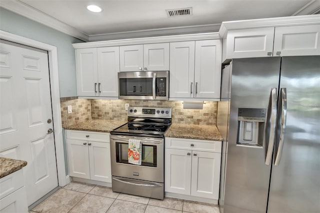 kitchen featuring appliances with stainless steel finishes, light tile patterned floors, white cabinetry, and dark stone counters