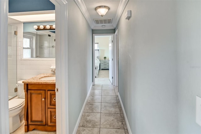 hall featuring light tile patterned floors, tile walls, ornamental molding, and sink