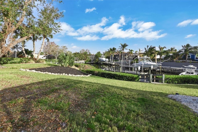 view of home's community with a boat dock, a water view, and a yard