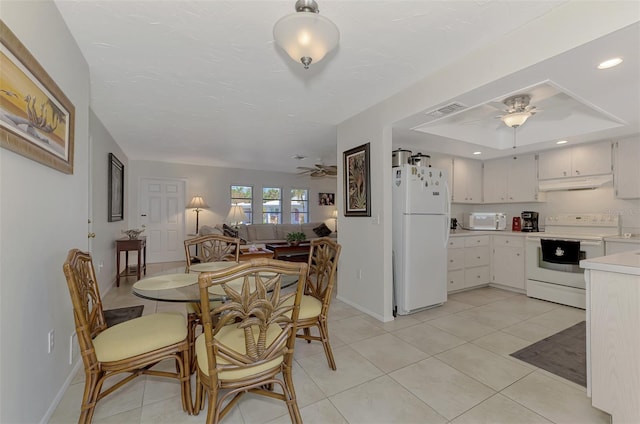 dining area featuring light tile patterned flooring, a tray ceiling, and ceiling fan