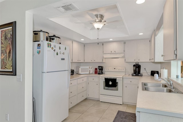 kitchen featuring white appliances, sink, light tile patterned flooring, a tray ceiling, and ceiling fan