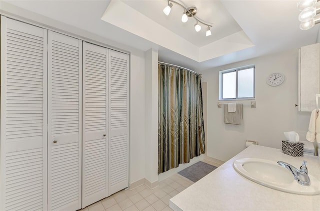 bathroom with vanity, a tray ceiling, and tile patterned flooring