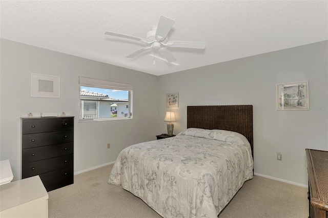 bedroom with ceiling fan, light carpet, and a textured ceiling