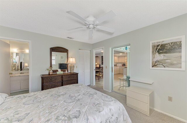 carpeted bedroom featuring a closet, ceiling fan, a textured ceiling, and ensuite bath