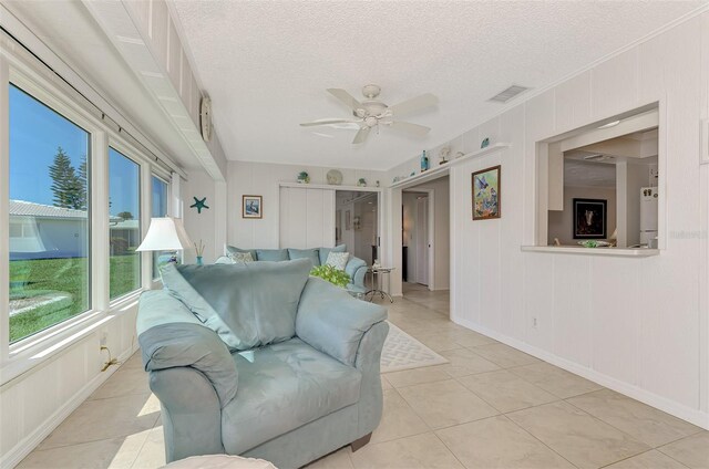 tiled living room with ceiling fan and a textured ceiling