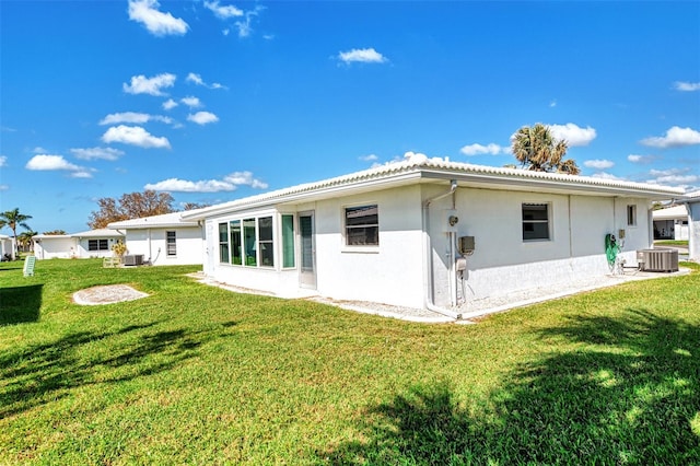 back of property featuring central AC and a lawn