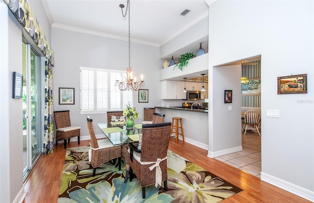649 Crossfield Cir Unit 10, Venice, FL 34293 - dining area with light wood-style floors, a chandelier, crown molding, a towering ceiling, and baseboards