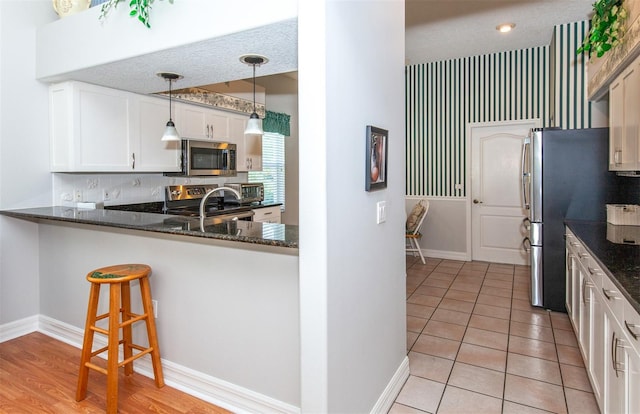 649 Crossfield Cir Unit 10, Venice, FL 34293 - kitchen with appliances with stainless steel finishes, dark stone counters, baseboards, white cabinets, and hanging light fixtures