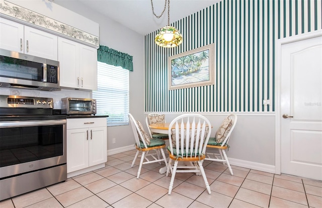 649 Crossfield Cir Unit 10, Venice, FL 34293 - kitchen with appliances with stainless steel finishes, baseboards, light tile patterned flooring, and white cabinets