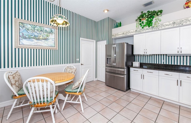 649 Crossfield Cir Unit 10, Venice, FL 34293 - kitchen with stainless steel fridge, wallpapered walls, white cabinetry, light tile patterned floors, and hanging light fixtures