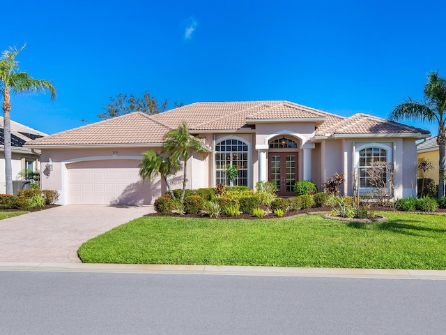 mediterranean / spanish home with a front lawn, a garage, and french doors