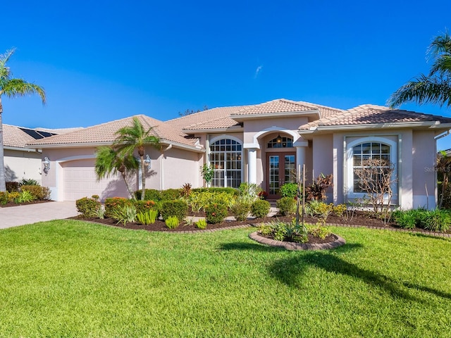 mediterranean / spanish house with a front yard, french doors, and a garage