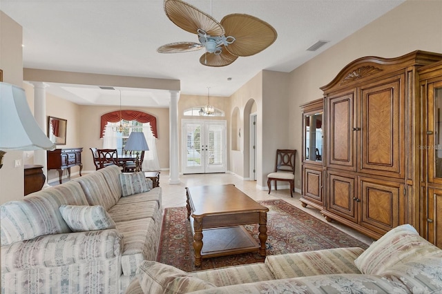 living room with french doors, ceiling fan with notable chandelier, and decorative columns