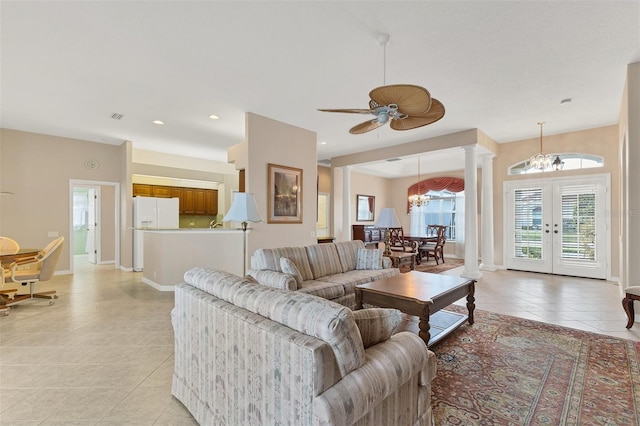 tiled living room featuring ceiling fan with notable chandelier, french doors, and decorative columns