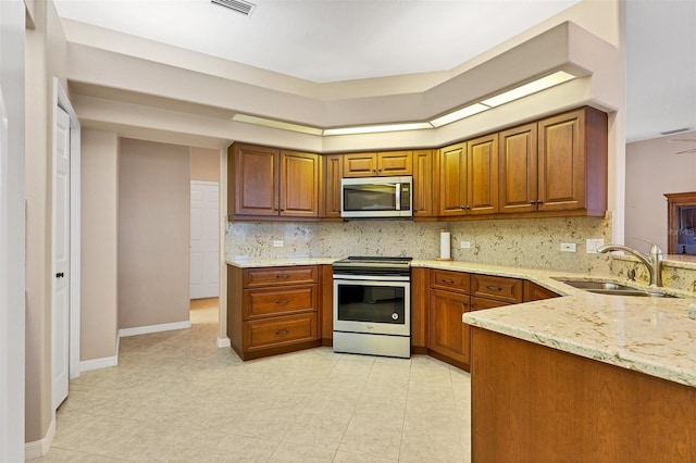 kitchen featuring decorative backsplash, appliances with stainless steel finishes, light stone counters, sink, and light tile patterned floors