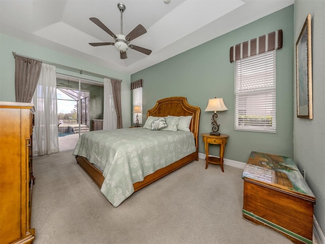 carpeted bedroom featuring access to outside, multiple windows, ceiling fan, and a raised ceiling