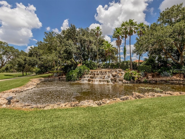 view of home's community with a water view and a lawn