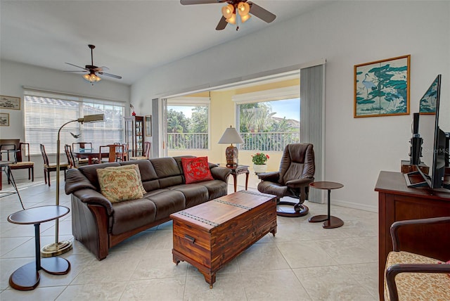 living room featuring lofted ceiling, light tile patterned flooring, and ceiling fan