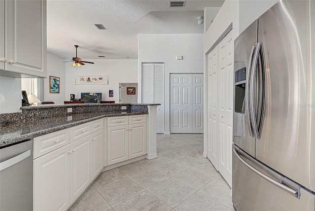 kitchen with dark stone countertops, white cabinetry, light tile patterned floors, appliances with stainless steel finishes, and a textured ceiling