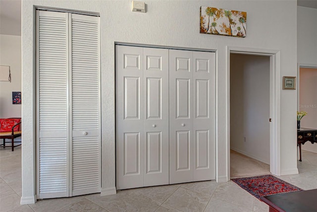 bedroom with multiple closets and light tile patterned floors