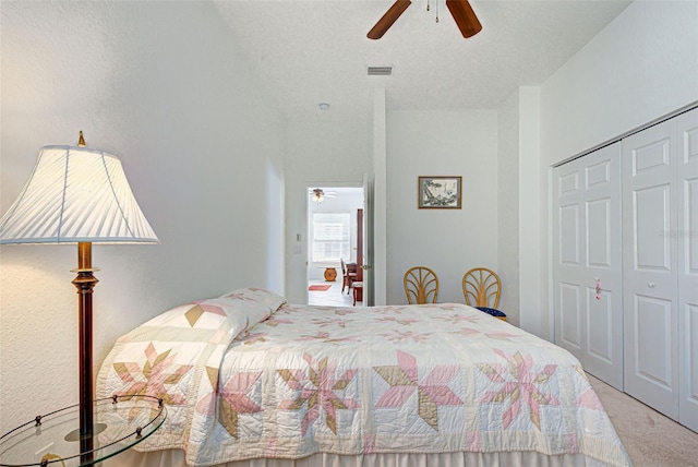 bedroom with a closet, ceiling fan, carpet flooring, and a textured ceiling