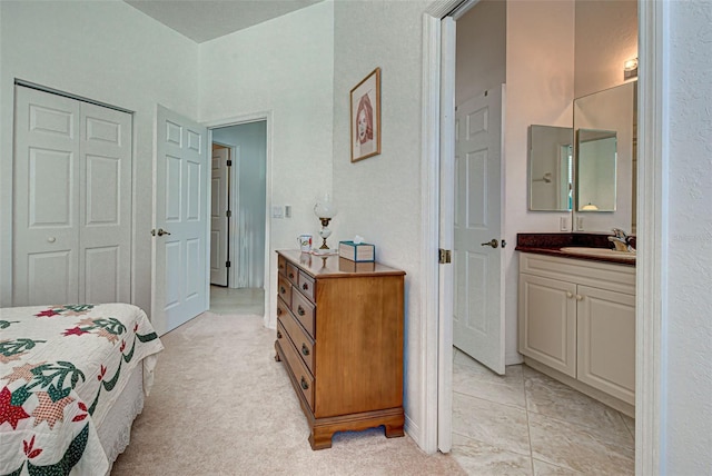 bedroom featuring a closet, sink, and light colored carpet