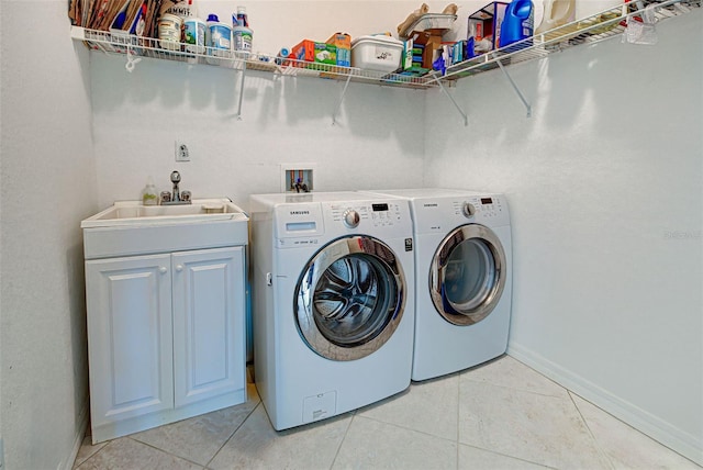 laundry area featuring cabinets, sink, washing machine and clothes dryer, and light tile patterned floors