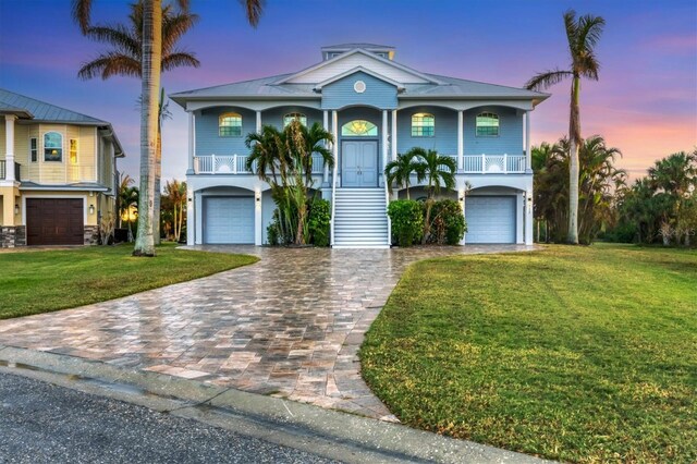 coastal home with a garage, a porch, and a yard