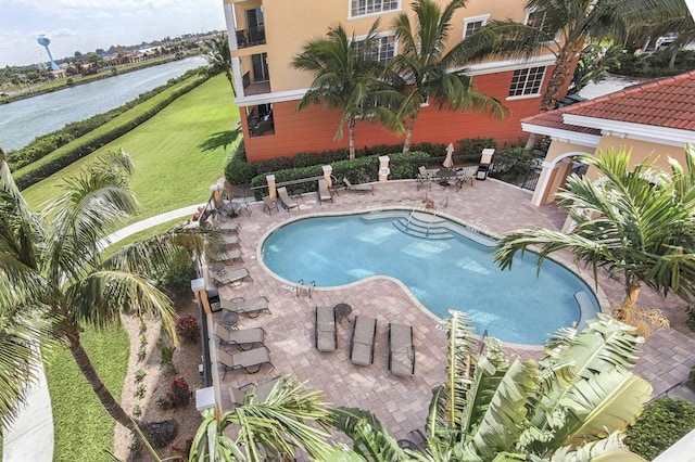 view of swimming pool with a patio area, a lawn, and a water view