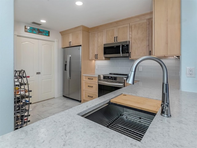 147 Tampa Ave E Unit 202, Venice, FL 34285 - kitchen featuring stainless steel appliances, light brown cabinetry, a sink, decorative backsplash, and light marble finish flooring