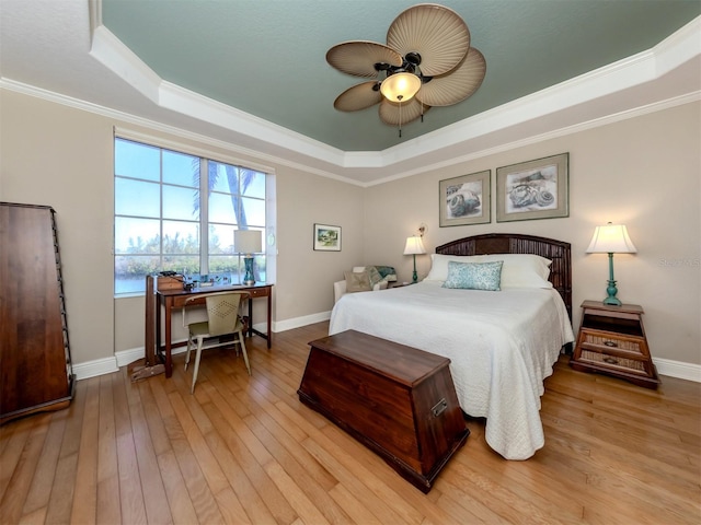 bedroom featuring ornamental molding, light hardwood / wood-style floors, a raised ceiling, and ceiling fan