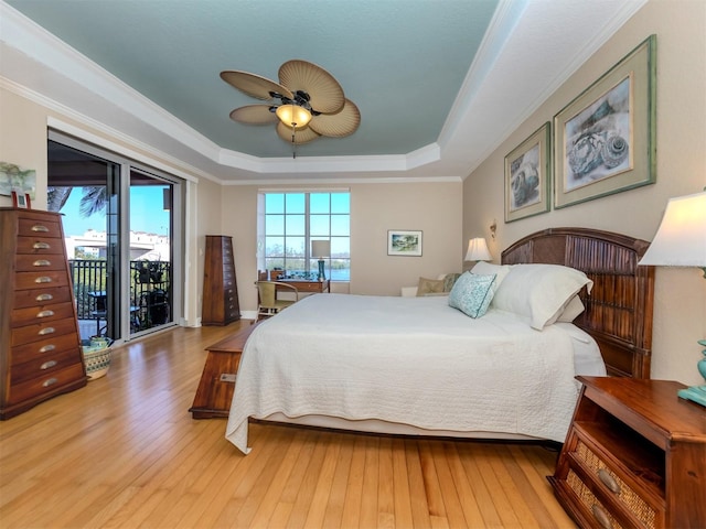 bedroom with access to outside, a tray ceiling, hardwood / wood-style floors, ceiling fan, and ornamental molding