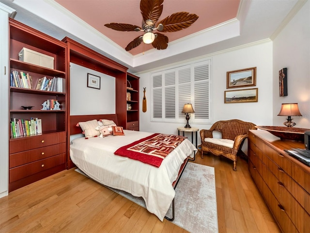 bedroom with a raised ceiling, ornamental molding, ceiling fan, and light wood-type flooring