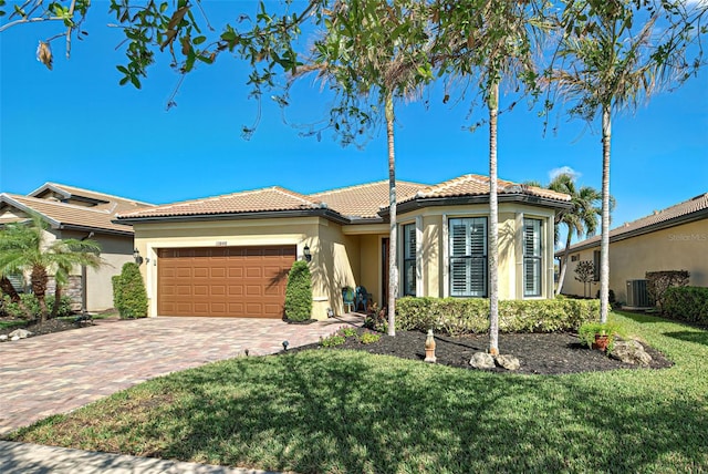 mediterranean / spanish house with central AC unit, a garage, and a front lawn