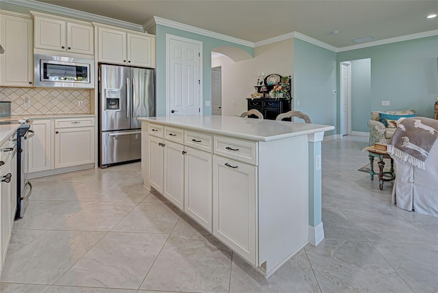 kitchen with ornamental molding, appliances with stainless steel finishes, tasteful backsplash, and a kitchen island