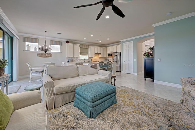 living room with ceiling fan with notable chandelier, light tile patterned floors, and crown molding